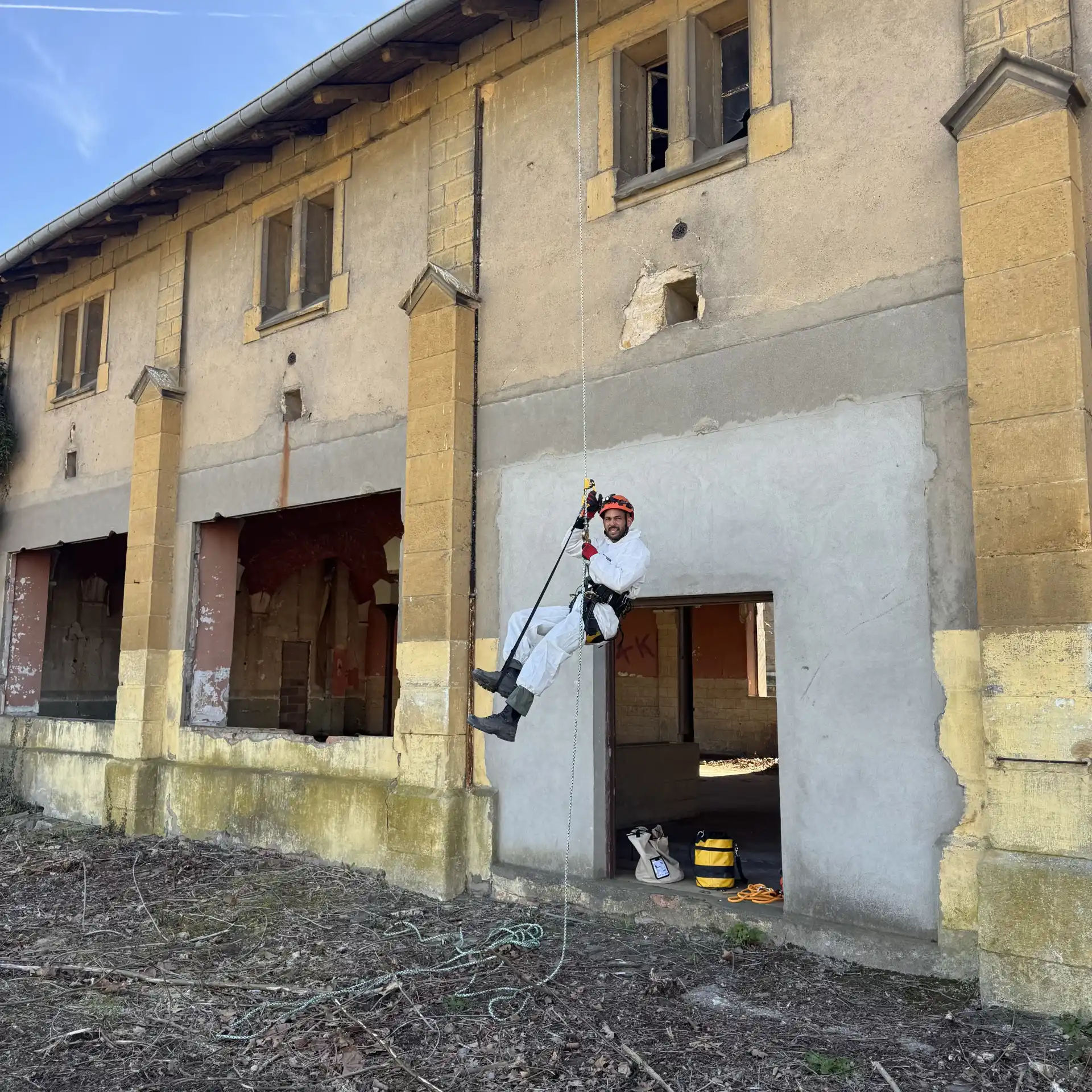 Technicien en descente sur corde le long de la façade d'un bâtiment ancien